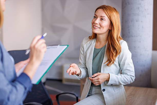 Confident professional woman discussing mastering behavioral interview questions with an interviewer holding a clipboard in a modern office setting